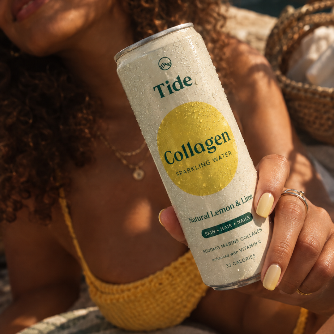 A close-up lifestyle shot of a person holding a can of Tide Collagen Sparkling Water. The can is white with a prominent yellow circle graphic and green text, covered in condensation.